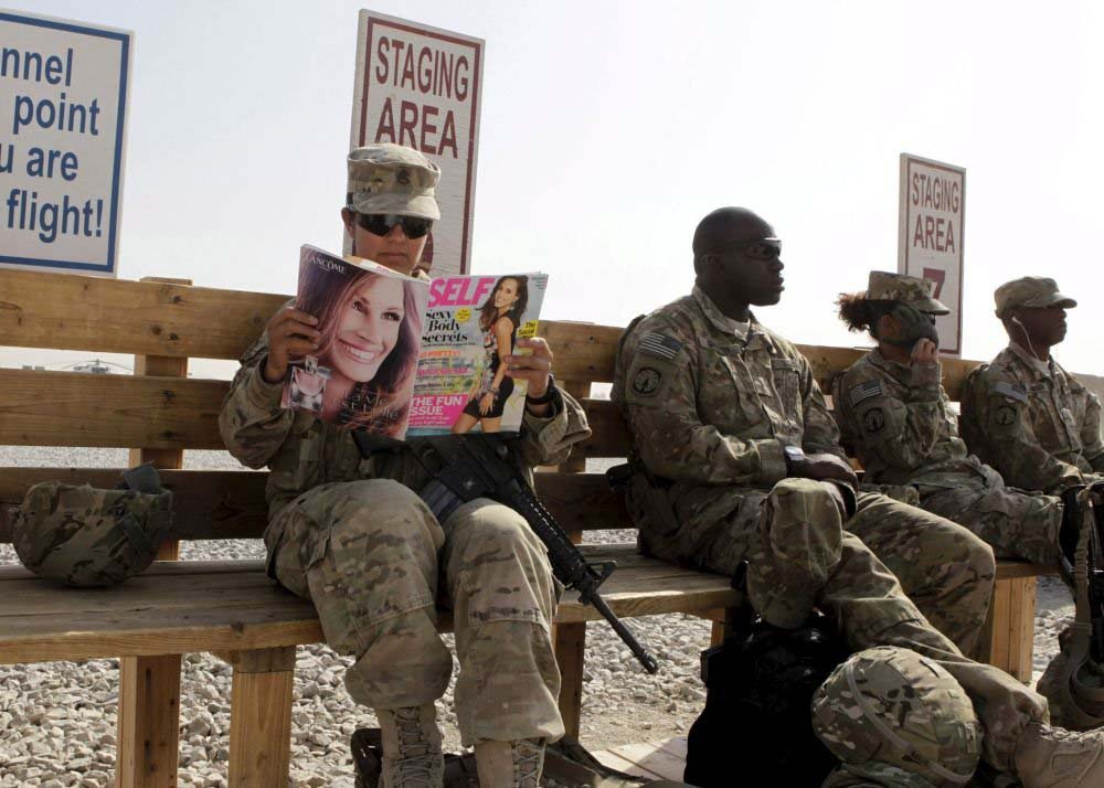 Afganistan'ındaki Kandahar üssünde, kendilerini diğer üsse transfer edecek helikopteri bekleyen ABD askeri Norma Gonzalez, bu boş vaktini dergi okuyarak değerlendiriyor.