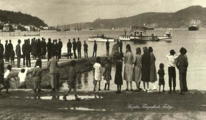 Kıyıda bekleyen Büyükdere ahalisi, bayramlık giysilerini giymiş, Brindisi'den kalkan deniz uçağının yanaşmasını bekliyor. Aero Espresso İtalyana şirketi 1923'te kurulmuş, Brindisi- Atina-İstanbul hattını ise 1926 yılında oluşturmuş...