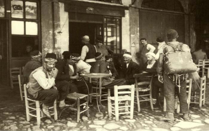 Bir İstanbul Kıraathanesi... Ortada bir masa, hasır tabure ve sandalyeler etrafına dizili... İki hoca, bir hamal ve taşradan gelenler..
